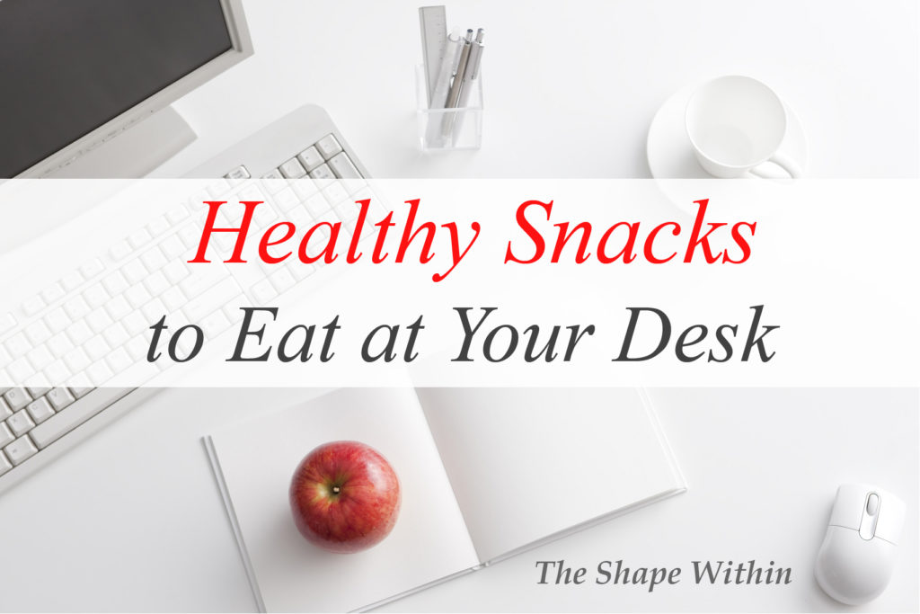 A red apple near a white computer- Just one of the many healthy snacks to eat at your desk
