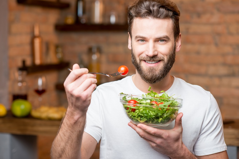 A fit man eating salad. How eating healthy food makes you lose weight | This content was originally written on TheShapeWithin.com