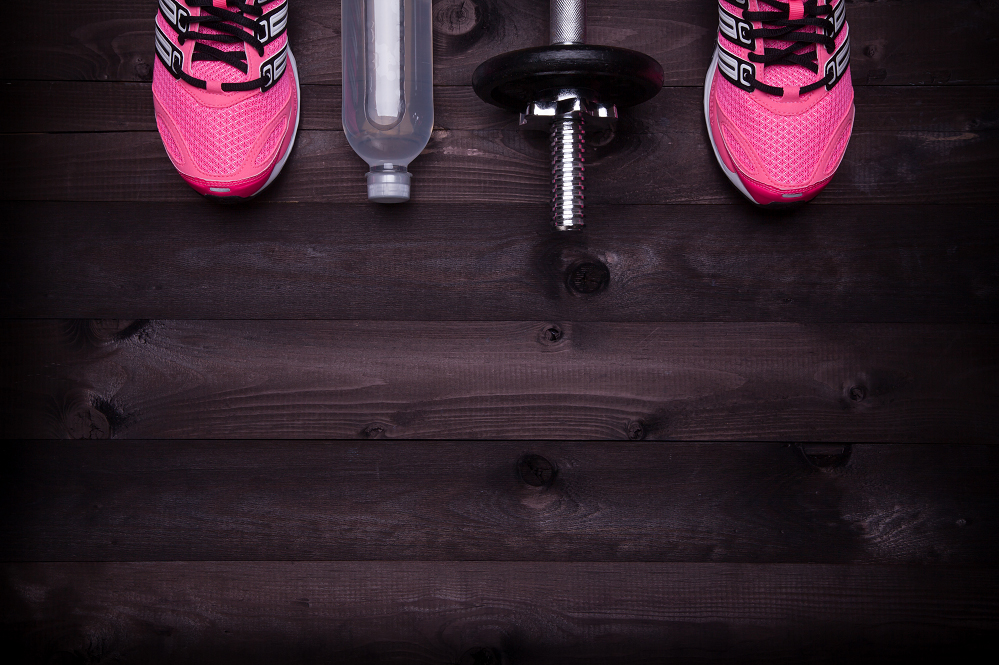 A pair of pink shoes sitting next to a water bottle and weights- Why you are exercising but not losing fat even though you are trying really hard