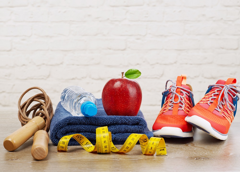 A pair of shoes, a water bottle, a jump rope, and an apple all sitting together